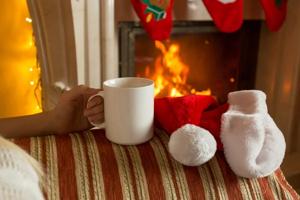 Closeup photo of woman sitting with cup of tea on sofa at firepl — Stock Photo, Image