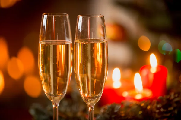 Closeup of two glasses of Champagne in front of burning candles — Stock Photo, Image