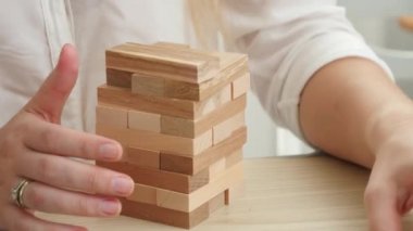 İş kadını ahşap oyuncak blokları ve tuğlalarıyla yüksek kule inşa ediyor. Geliştirme, başarı ve iş büyümesi kavramı.