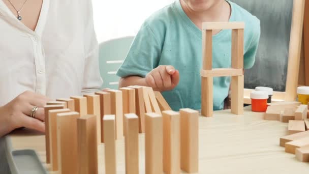 Långsam rörelse av pojke driver träblock och starta dominoeffekt. Träklossar som faller i kedja. Begreppet utbildning för barn i hemmet under inlåsning och vistelse i hemmet — Stockvideo