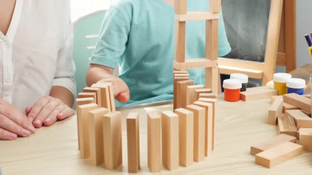 Långsam rörelse video av träblock och tegel faller i dominoeffekt. Barn leker med träleksaker. Begreppet utbildning för barn i hemmet under inlåsning och vistelse i hemmet — Stockvideo