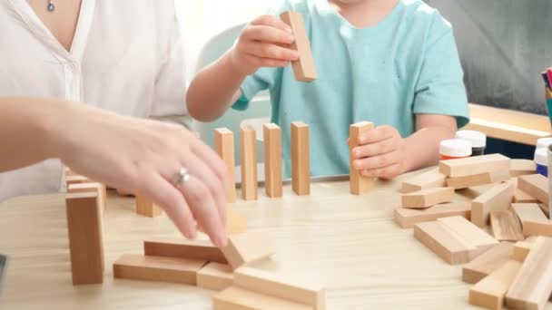 Anak kecil menaruh balok kayu atau domino dalam antrean panjang. Konsep pendidikan anak-anak di rumah selama kuncian dan tinggal di rumah. orangtua bermain dengan anak-anak — Stok Video
