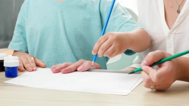 Vidéo rapprochée de l'enseignant enseignant enseignant le dessin et la peinture petit garçon au crayon. Mère éduquant et enseignant son fils à la maison. Écriture d'enfant avec crayon — Video