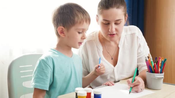 Matka učí kreslit a psát malému synovi. Boy learning writing with pencil at home Koncepce vzdělávání a odlehlé školy doma při uzamčení a sebeizolaci. — Stock video