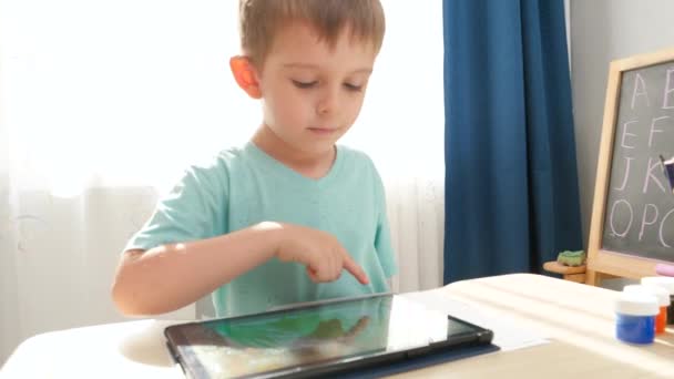 Retrato de sorrir menino feliz jogando no computador tablet digital depois de estudar e fazer lição de casa em casa. — Vídeo de Stock