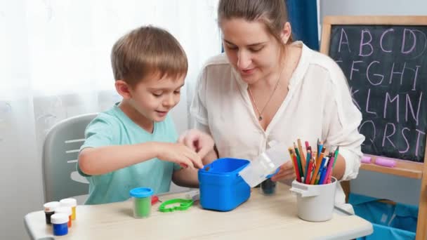 Glücklicher kleiner Junge mit Mutter, die mit bunten Briefmarken und Knetmasse spielt. Bildung und Lernen der Kinder zu Hause. Eltern spielen und unterrichten Kinder — Stockvideo