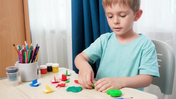 Criança sorridente menino moldar e esculpir formas e formas com massa colorida ou plasticina. Usando argila de brinquedo na educação e aprendizagem em casa — Vídeo de Stock