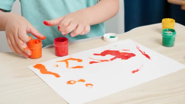 Nahaufnahme eines kleinen Jungen, der mit bunter Gouachefarbe auf weißem Papier bemalt wird. Konzept der Kindererziehung, Kreativitätsentwicklung und Kunst. — Stockvideo
