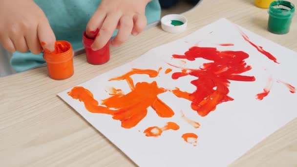 Primo piano di bambino che dipinge e disegna con le dita su carta bianca. Concetto di educazione dei bambini, sviluppo della creatività e arte. — Video Stock