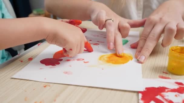 Primer plano de vídeo de la madre y el niño pequeño dibujo de la imagen con los dedos cubiertos de pintura de colores. La familia se divierte. COncept de arte, creatividad y aprendizaje infantil — Vídeo de stock