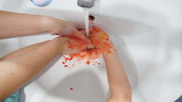 Closeup of little boy washing colorful paint off his hands after drawing with fingers. Concept of fun and creativity. — Stock Video