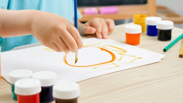 Primo piano del piccolo bambino disegno immagine ragazzo con vernice colorata con pennello. Educazione dei bambini a casa durante l'autoisolamento e l'isolamento. Concetto di arte e creatività dei bambini — Foto Stock