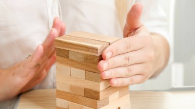 İş kadını ahşap oyuncak blokları ve tuğlalarıyla yüksek kule inşa ediyor. Geliştirme, başarı ve iş büyümesi kavramı.