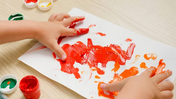Крупный план красочного рисунка, нарисованного детскими пальцами. Маленький мальчик рисует красочной гуашью — стоковое фото