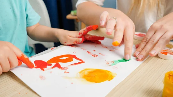Closeup βίντεο της μητέρας και του μικρού γιου σχέδιο εικόνα με τα δάχτυλα καλύπτονται με πολύχρωμο χρώμα. Η οικογένεια διασκεδάζει. Αντίληψη της τέχνης, της δημιουργικότητας και της μάθησης των παιδιών — Φωτογραφία Αρχείου