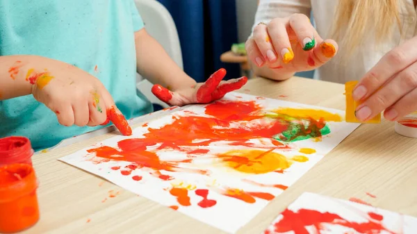 Κλείσιμο του σχεδίου ενηλίκων και παιδιών με τα χέρια και τα δάχτυλα χρησιμοποιώντας πολύχρωμο χρώμα σε λευκό χαρτί. Έννοια της δημιουργικής εκπαίδευσης και της ανάπτυξης δεξιοτήτων τέχνης — Φωτογραφία Αρχείου