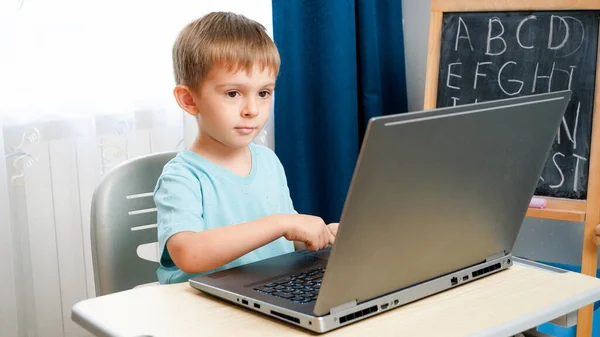 Criança sorrindo menino abre laptop e ligá-lo. Criança usando computadores e gadgets para educação e fazer lição de casa. — Fotografia de Stock