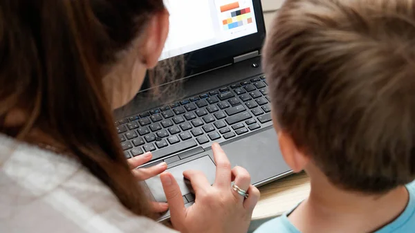 Visão traseira da mãe com o pequeno filho sentado atrás do laptop e estudando. CHild usando computador para educação e aprendizagem — Fotografia de Stock