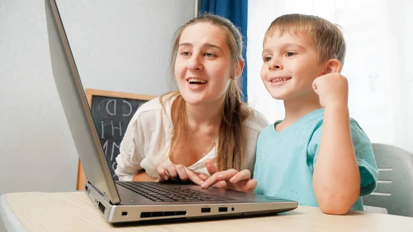 Mãe sorridente feliz com o filho pequeno usando laptop e olhando na tela do computador. — Fotografia de Stock