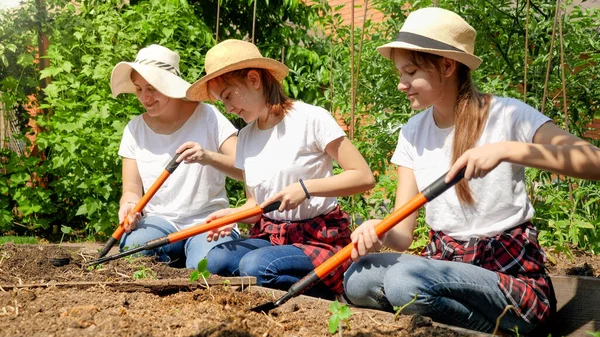 Mosolygó lányok anyával termő talaj és ásni gödröt kerti ágy ültetésére új növényi palánták és csírák. Egészséges és bio zöldségek termesztése otthon — Stock Fotó