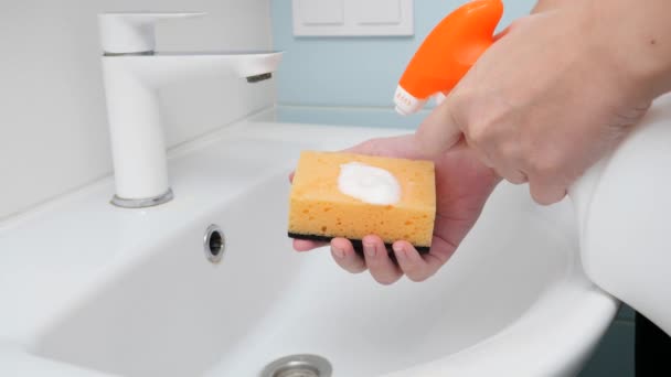 Coseup de mujer joven rociando detergente o limpiador en la esponja y lavabo en el baño. Concepto de higiene y tareas domésticas — Vídeos de Stock