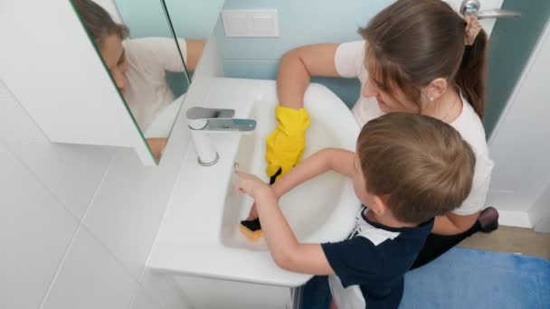 小さな息子の洗浄と洗浄バスルームの水シンクを持つ母親のトップビュー。家事や遊びを共にする家族 — ストック動画