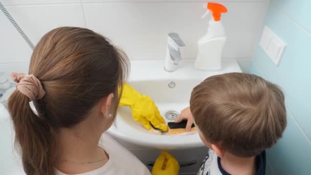 蹒跚学步的男孩和年轻母亲一起打扫浴室。做家务活和洗衣服的家庭 — 图库视频影像