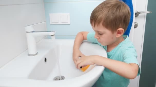 Menino pequeno lavando pia de água no banheiro ao fazer tarefas domésticas e ajudar os pais — Vídeo de Stock