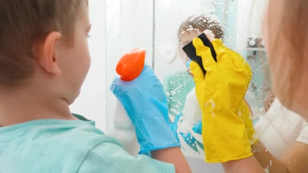 Close-up de mãe e filho pequeno limpeza e lavatório espelho no banheiro com esponjas e detergente químico — Vídeo de Stock