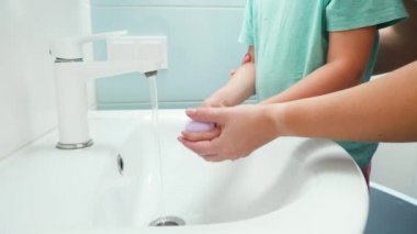 Oğullarının ellerini banyo lavabosunda sabunla yıkarken. Sağlık ve hijyen kavramı