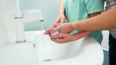 Küçük çocuk, genç annesiyle el pençe divan duruyor. Çocuk temizleme ve ellerini antibakteriyel sabun ve suyla yıkama