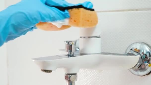 Closeup of hand in blue rubber glove washing and cleaning shiny metal water tap in bathroom while doing housework and cleanup at home — Stock Video