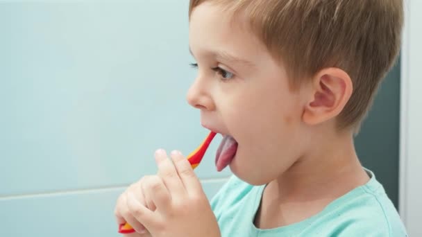 Portrait of little boy brushing teeth and cleaning tongue with toothbrush. CHild taking care of teeth and cleaning them — Stock Video