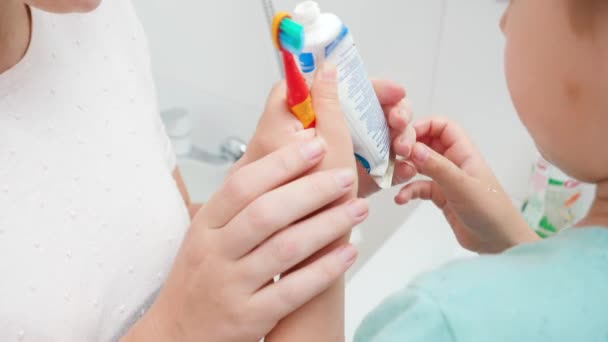 Fechar a boca da mãe a ajudar o filho a aplicar pasta de dentes. Criança usando escova de dentes e pasta de dentes para escovar e limpar os dentes — Vídeo de Stock