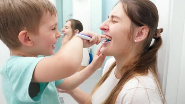 Criança engraçada menino limpeza e escovação de dentes mães. Conceito de higiene familiar e cuidados com os dentes — Vídeo de Stock