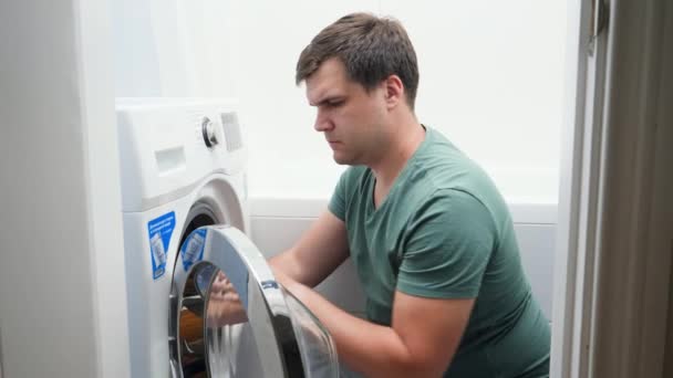 Uomo confuso impostazione lavatrice. Maschio lottando e frustrante durante il lavoro domestico e routine quotidiana a casa — Video Stock