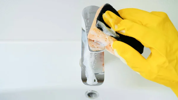 Bovenaanzicht van de vrouw in ruber handschoenen wassen en schoonmaken glanzend water kraan in badkamer wastafel — Stockfoto