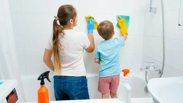 小さいです幼児男の子とともに若いですお母さん洗濯と掃除タイルの壁でバスルームで家事や家庭の掃除をしながら — ストック写真