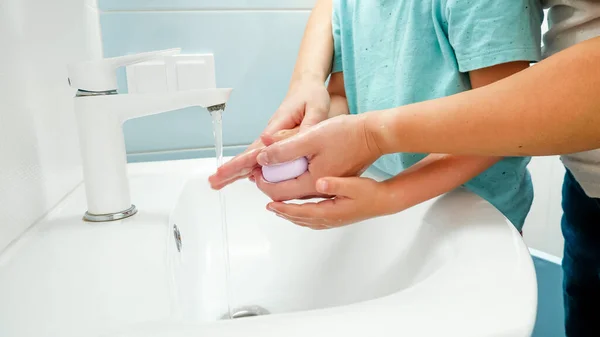 Küçük çocuk, genç annesiyle el pençe divan duruyor. Çocuk temizleme ve ellerini antibakteriyel sabun ve suyla yıkama — Stok fotoğraf