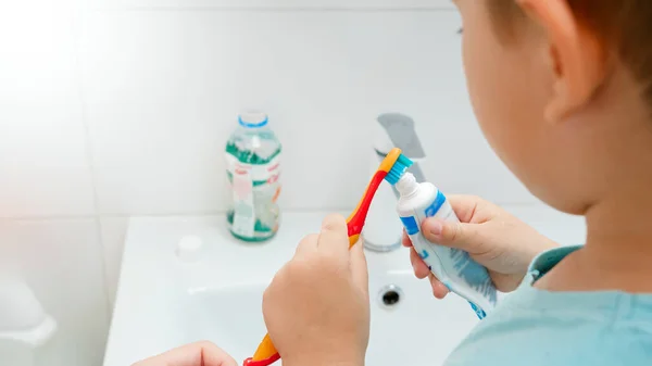 A kisfiú fogkrémet tett a fogkefére a fürdőszobában. — Stock Fotó