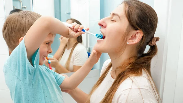 Pequeño niño pequeño cepillarse y limpiar los dientes a su madre en el baño — Foto de Stock