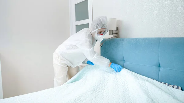 Koruyucu takım elbiseli otel hizmetçisi ve otel odasını temizleyen eldivenler. Kovid 19 ve koronavirüs salgını sırasında dezenfeksiyon ve hijyen. — Stok fotoğraf