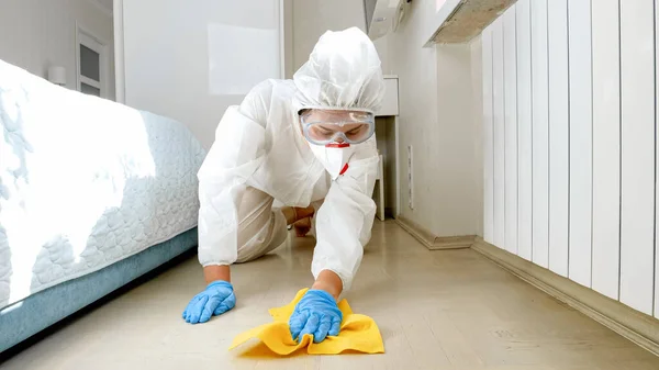 Koruyucu tıbbi kıyafet giyen ev hanımı evde yerleri yıkıyor ve temizliyor. Tecrit süresince dezenfeksiyon ve hijyen ve salgın hastalıklar. — Stok fotoğraf