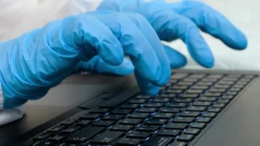 Laptopta çalışan koruyucu lastik eldivenli doktorlara yakın çekim. Tıbbi eldivenlerle klavye yazma ve kullanma