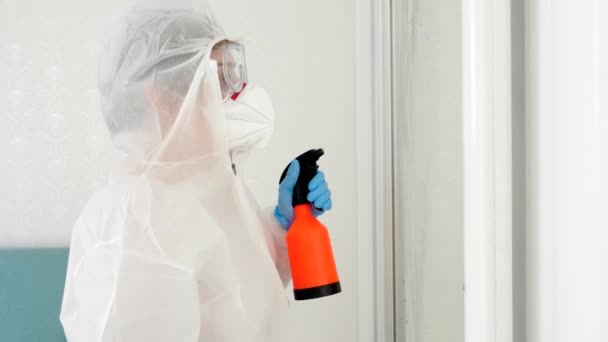 Portret osoby w ochronnym stroju medycznym używającej chemicznego sprayu do detergentów do dezynfekcji domu i mebli z wirusów i bakterii — Wideo stockowe