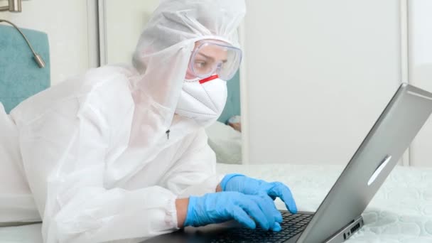 Femeia în costum de protecție biohazard lucrează de la distanță de acasă în timpul închiderii. Pandemie globală covid-19 și blocare — Videoclip de stoc