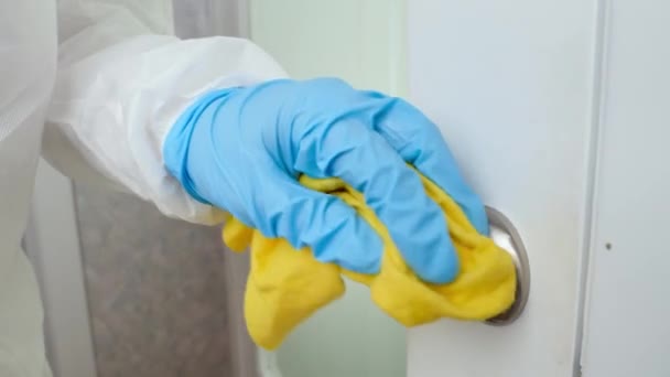 Κλείσιμο προσώπου με ιατρικά προστατευτικά γάντια που απολυμαίνουν και εφαρμόζουν αντισηπτικό στις χειρολαβές των θυρών στο σπίτι. Καταπολέμηση του coronavirus και του covid-19 — Αρχείο Βίντεο