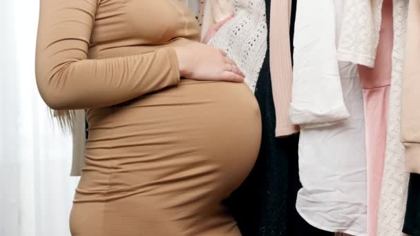 Zbliżenie pięknej kobiety w ciąży o zakupy i szuka ubrań dla matek kupić — Wideo stockowe