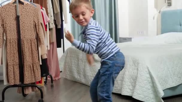 Zabawny 5-letni chłopiec maluch tańczy i robi miny w szafie w sypialni — Wideo stockowe
