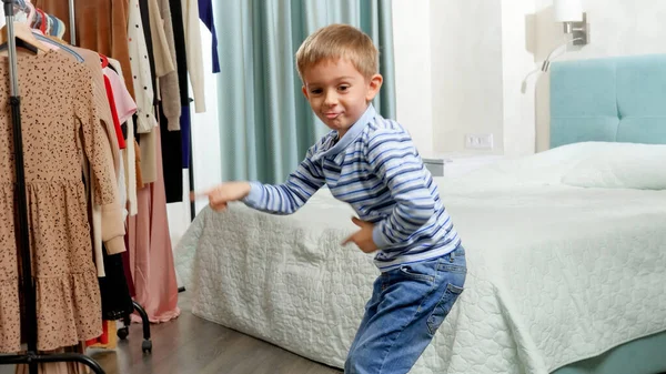 재밌는 5 살짜리 남자 아이가 춤을 추고 옷장에서 얼굴을 만들고 있는 모습 — 스톡 사진